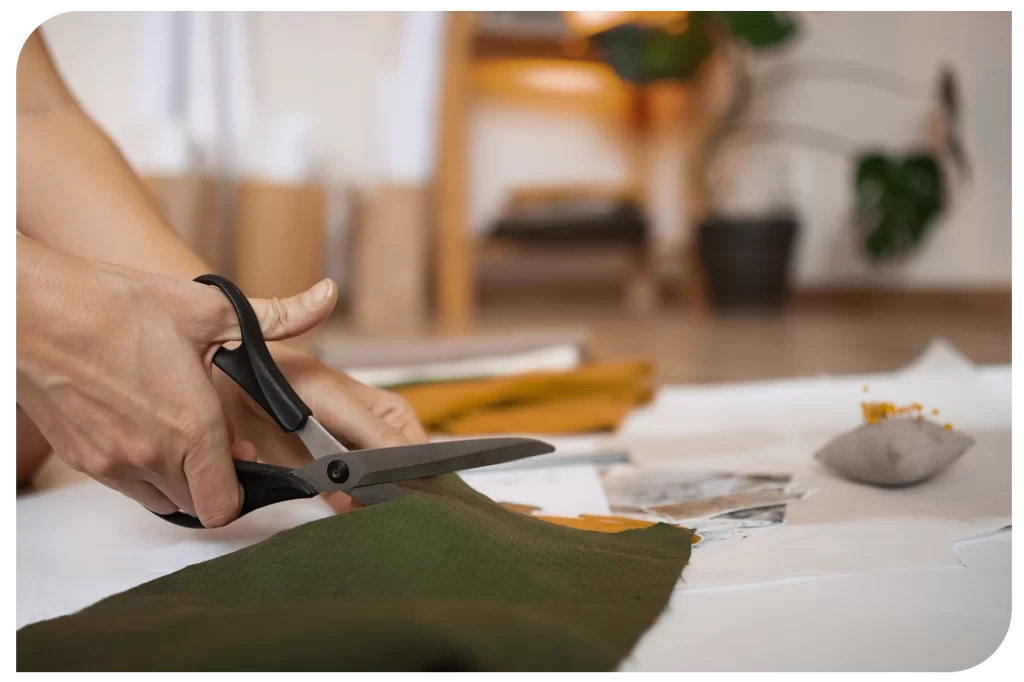 Pessoa cortando tecido para confecção de roupas. 