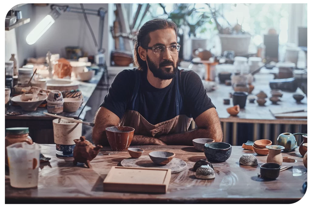 Homem em seu ateliê pensativo.