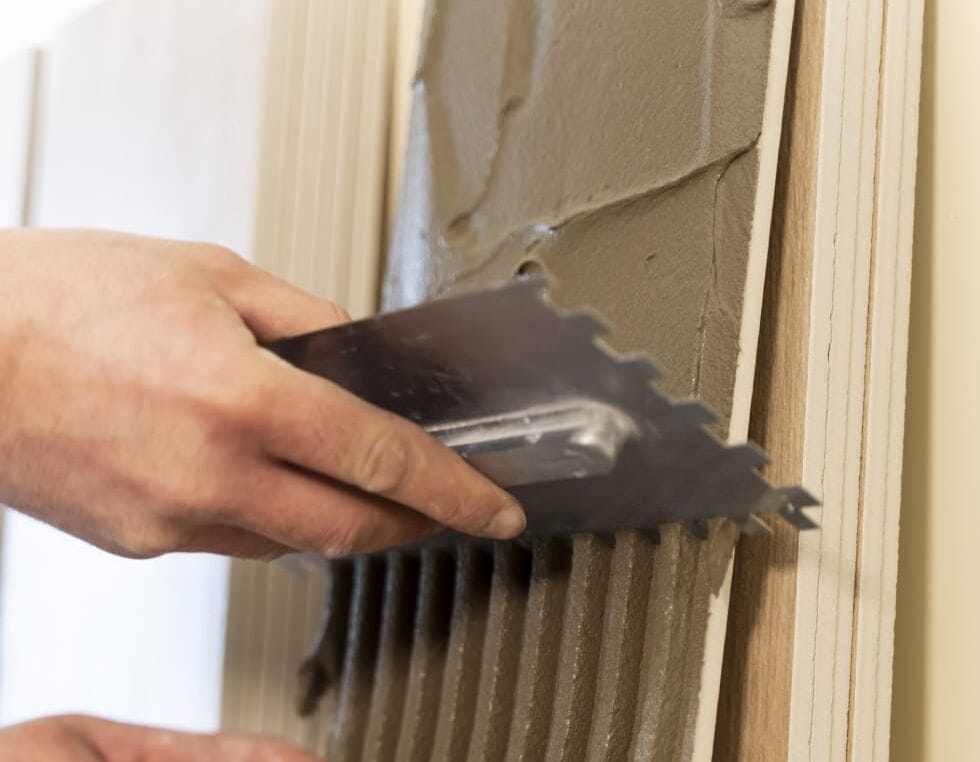 pessoa aplicando cimento no azulejo